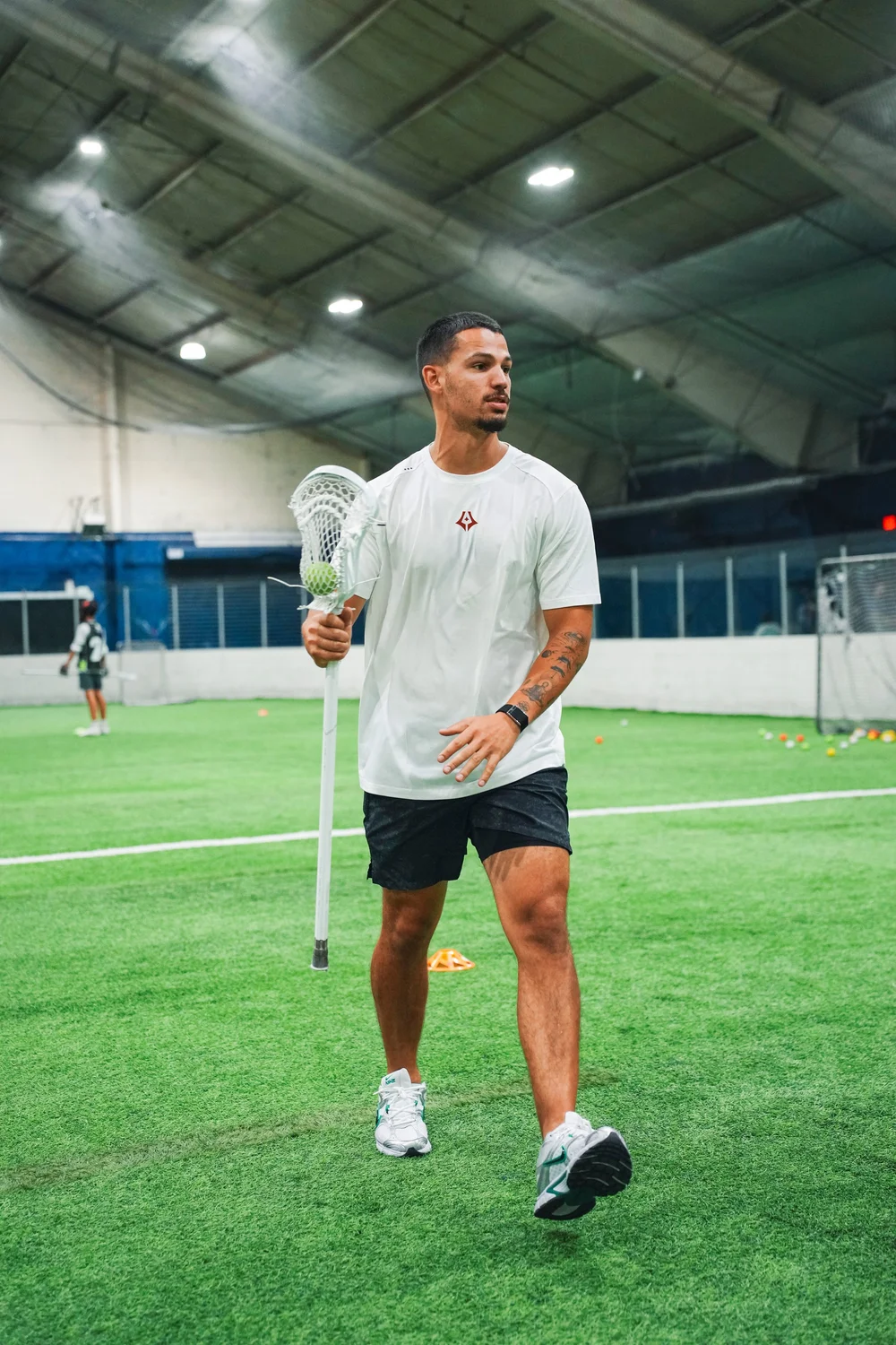 Jules Heningburg on the indoor lacrosse field with his stick