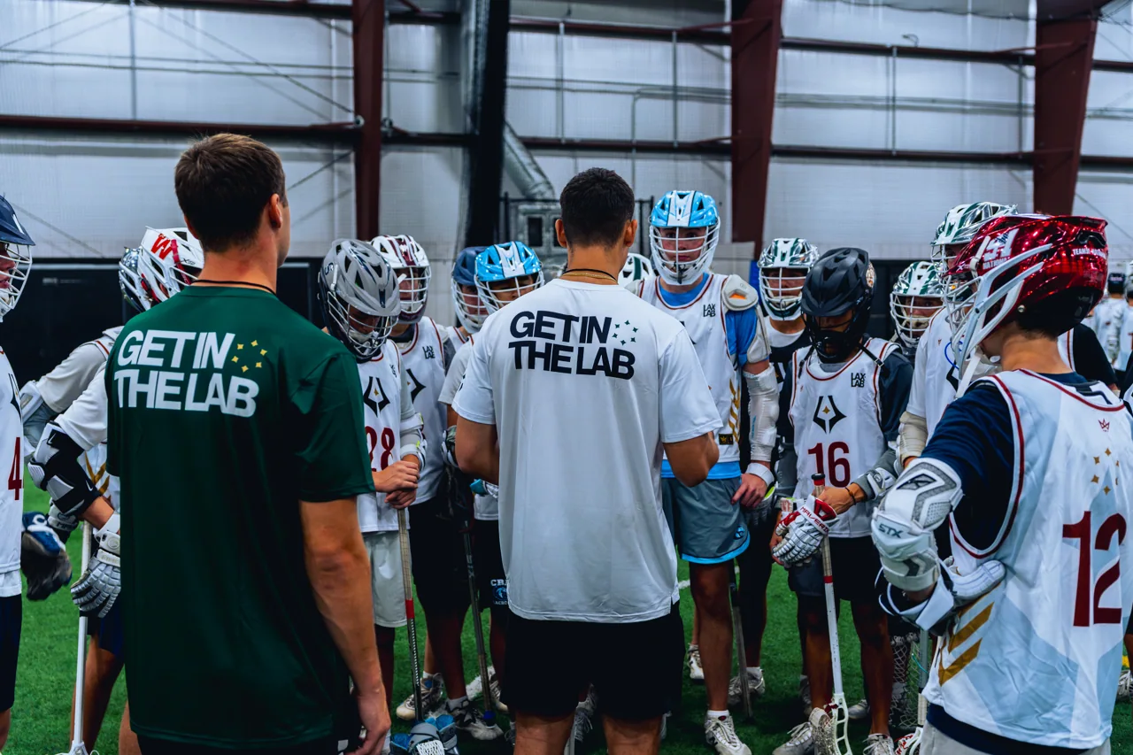 Coaches and young lacrosse players gather for a team talk