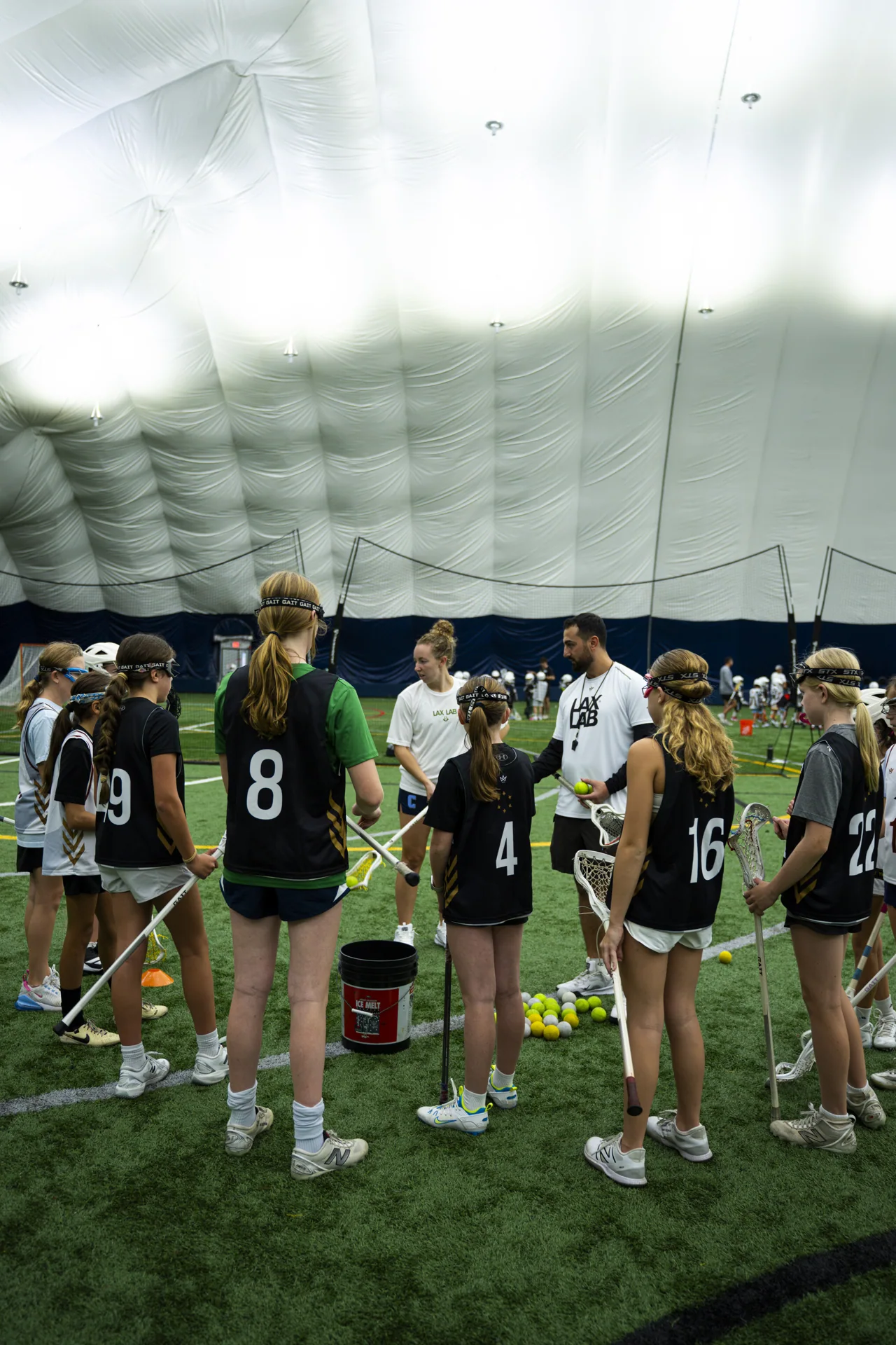A group of girls listening to their coach on an indoor field