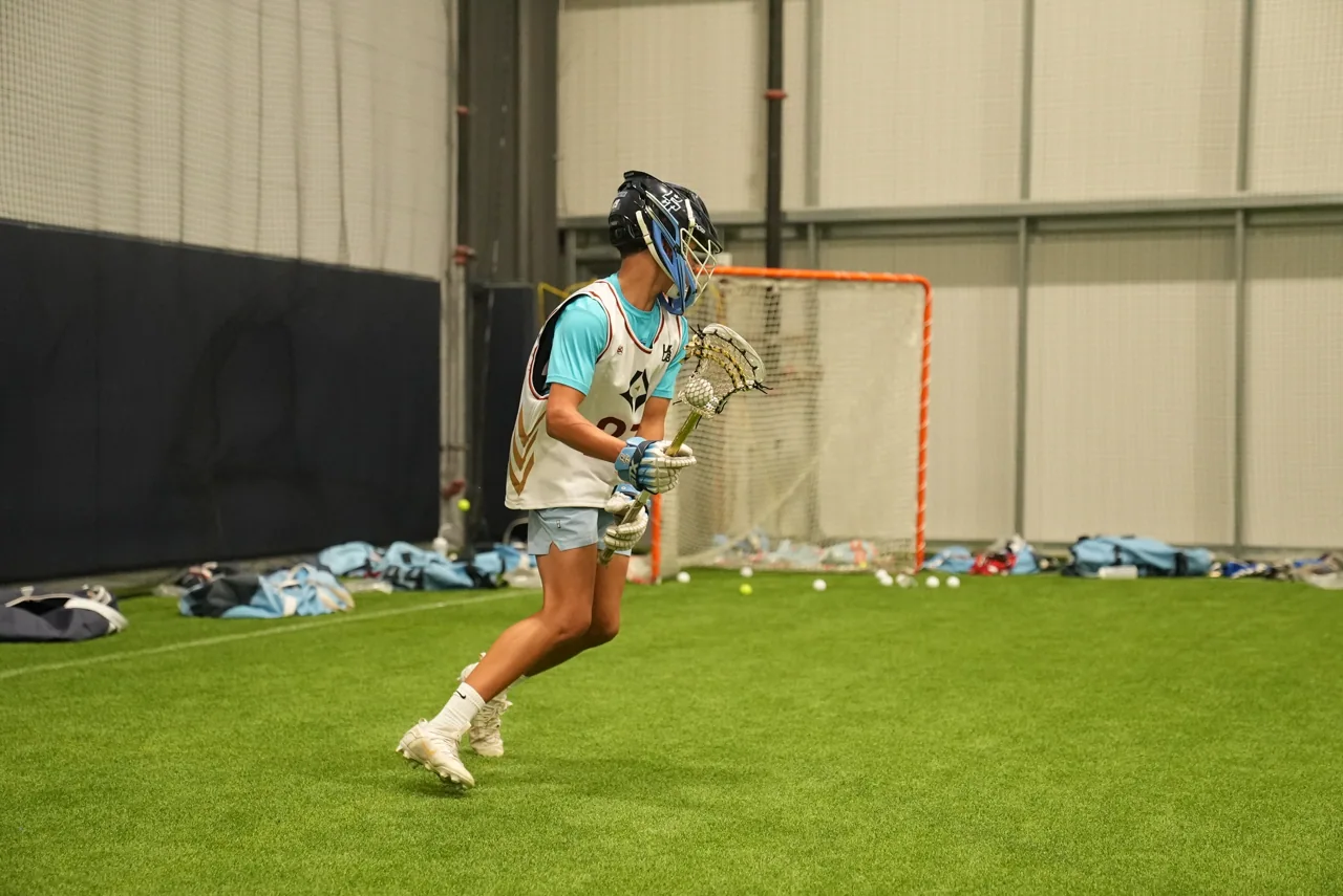 A lacrosse player works on her shot at an indoor goal