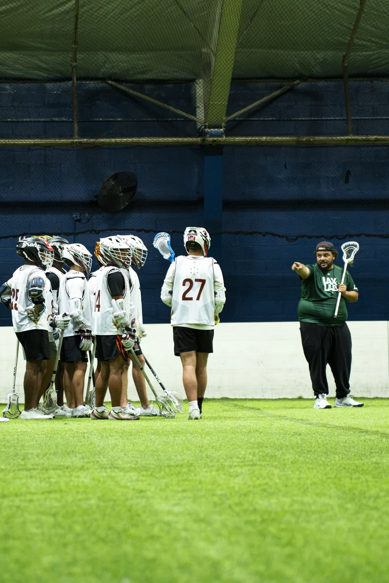 A coach addresses a group of athletes on the training field