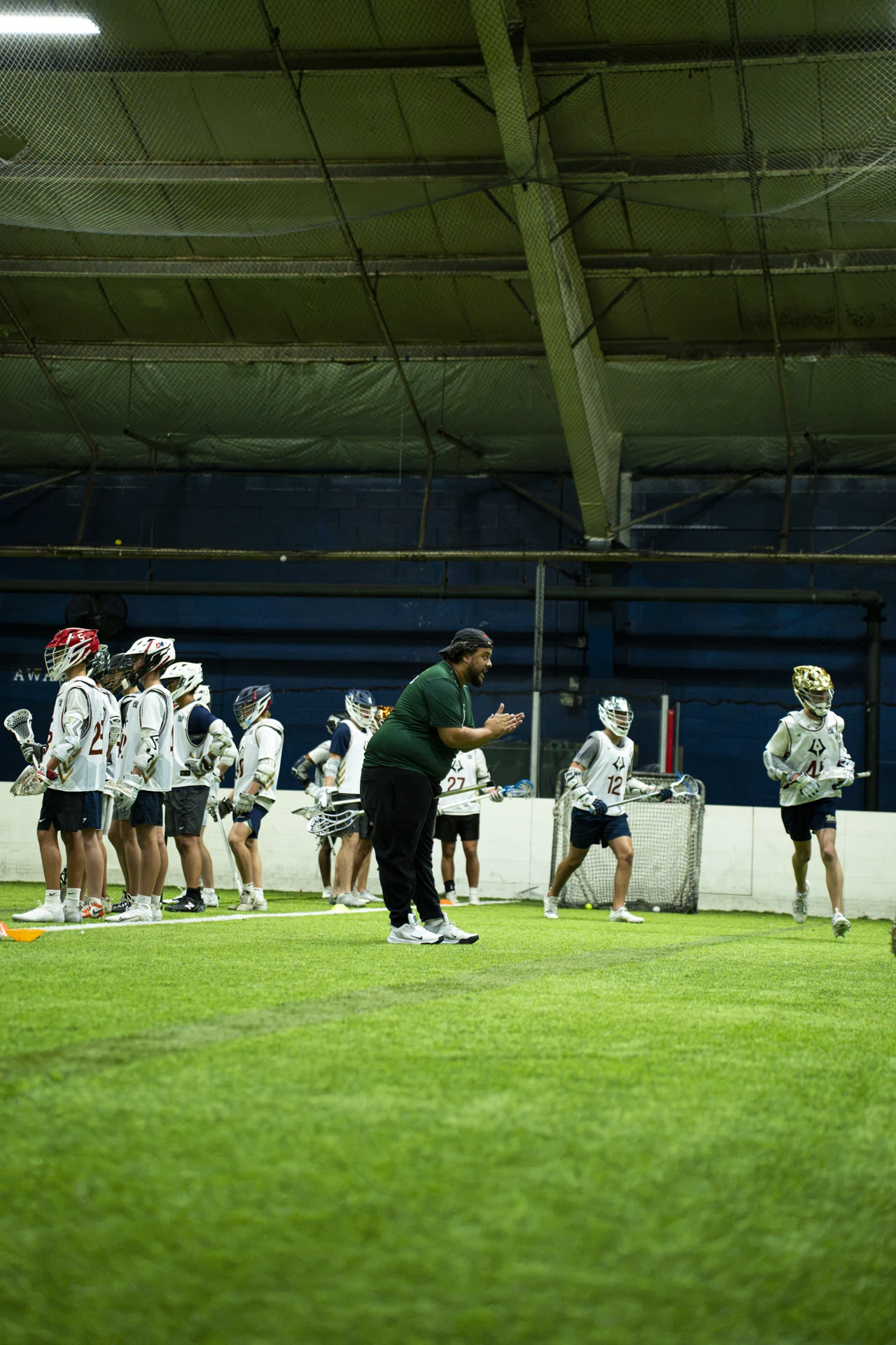A LAX LAB coach guides a group of young players during indoor lacrosse training